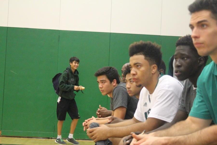 The boys basketball team watch the game carefully as their teammates dominate the court. 