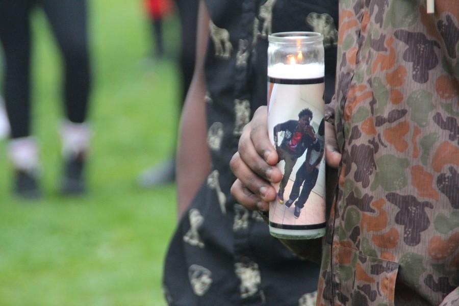 A young man holds a candle with Kendall Fosters picture on it, waiting to place it beside the memorial.